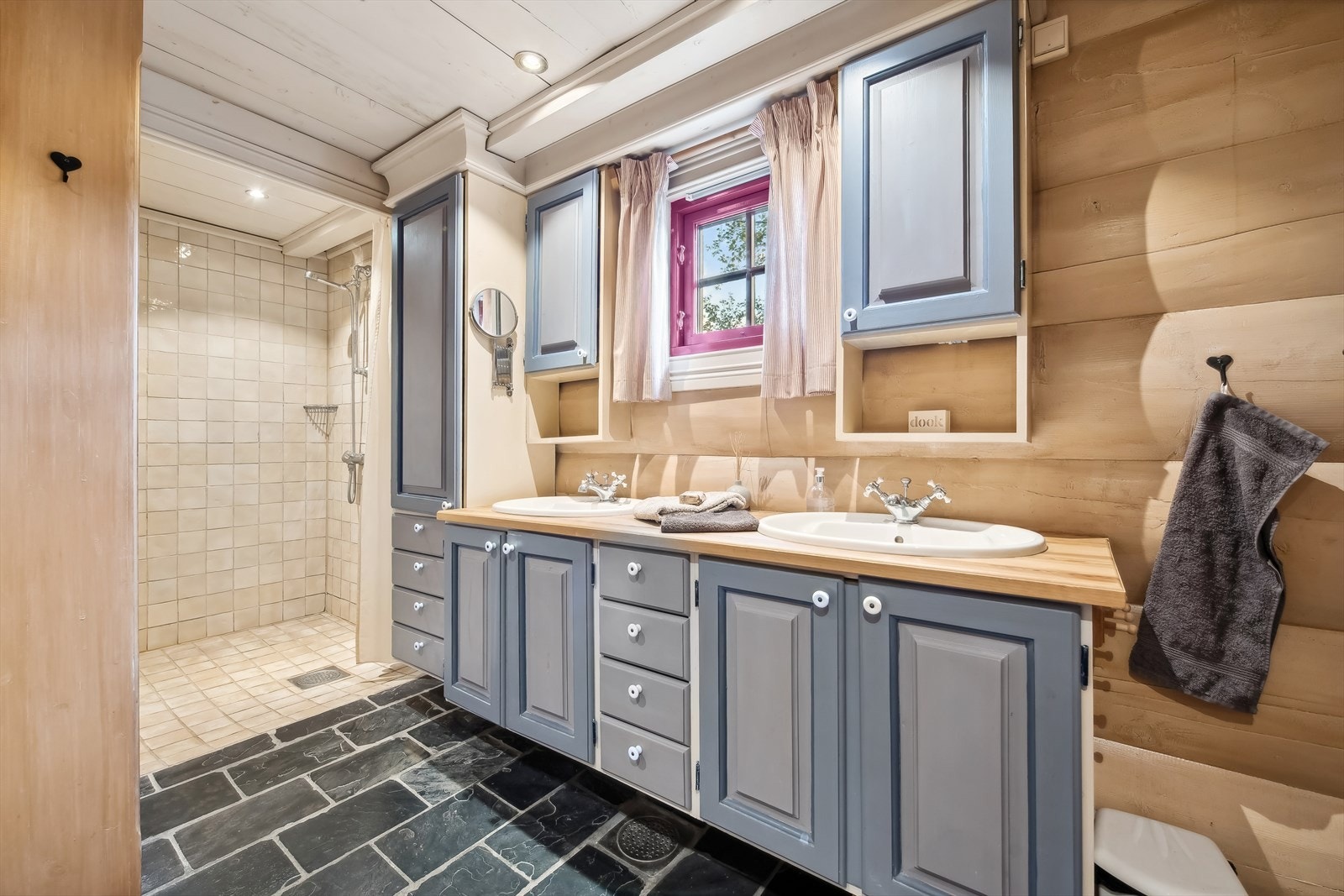 Hovedbadet i hovedetasjen er elegant utstyrt med baderomsinnredning som inkluderer nedfelte servanter, toalett og dusjnisje. Dusjnisjen har italienske porselensfliser på vegg, flis på gulv, og panel i himling. Galleribilde