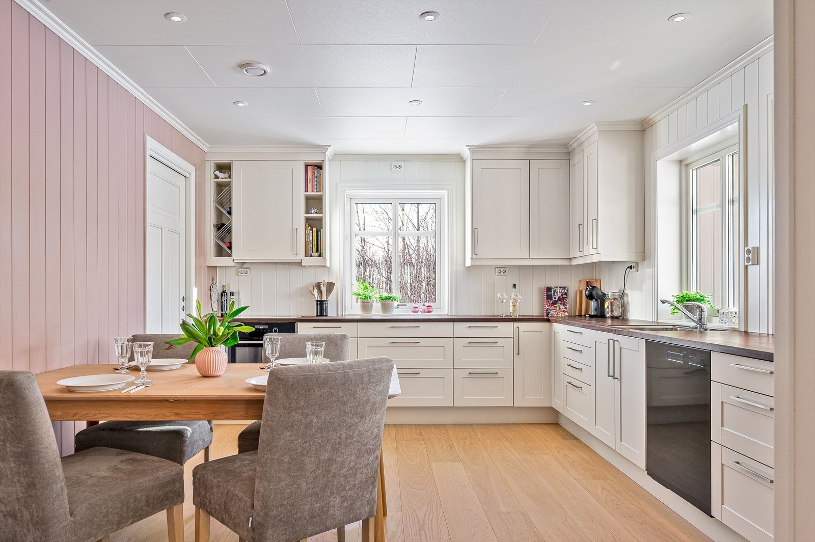 Stort, lyst og flott kjøkken med enstavs parkett på gulv, panelplater på veggene og downlights i himlingen. Galleribilde