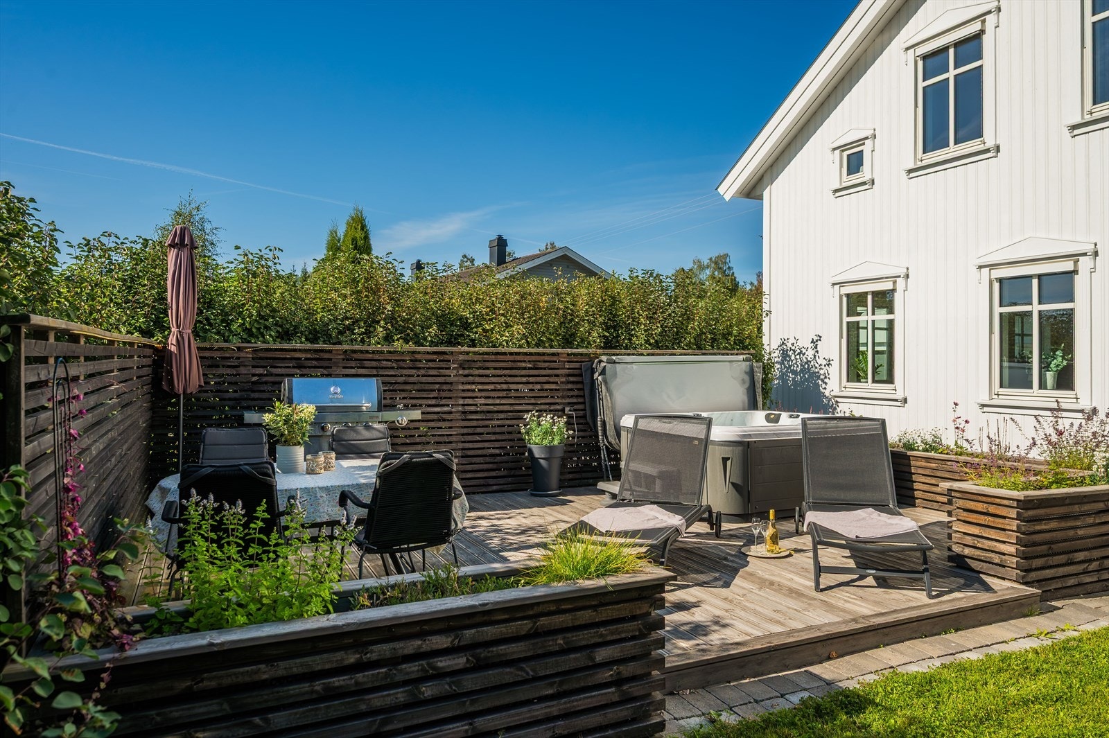 Skjermet of solrik terrasse innhegnet med levegger og blomsterkasser. Galleribilde