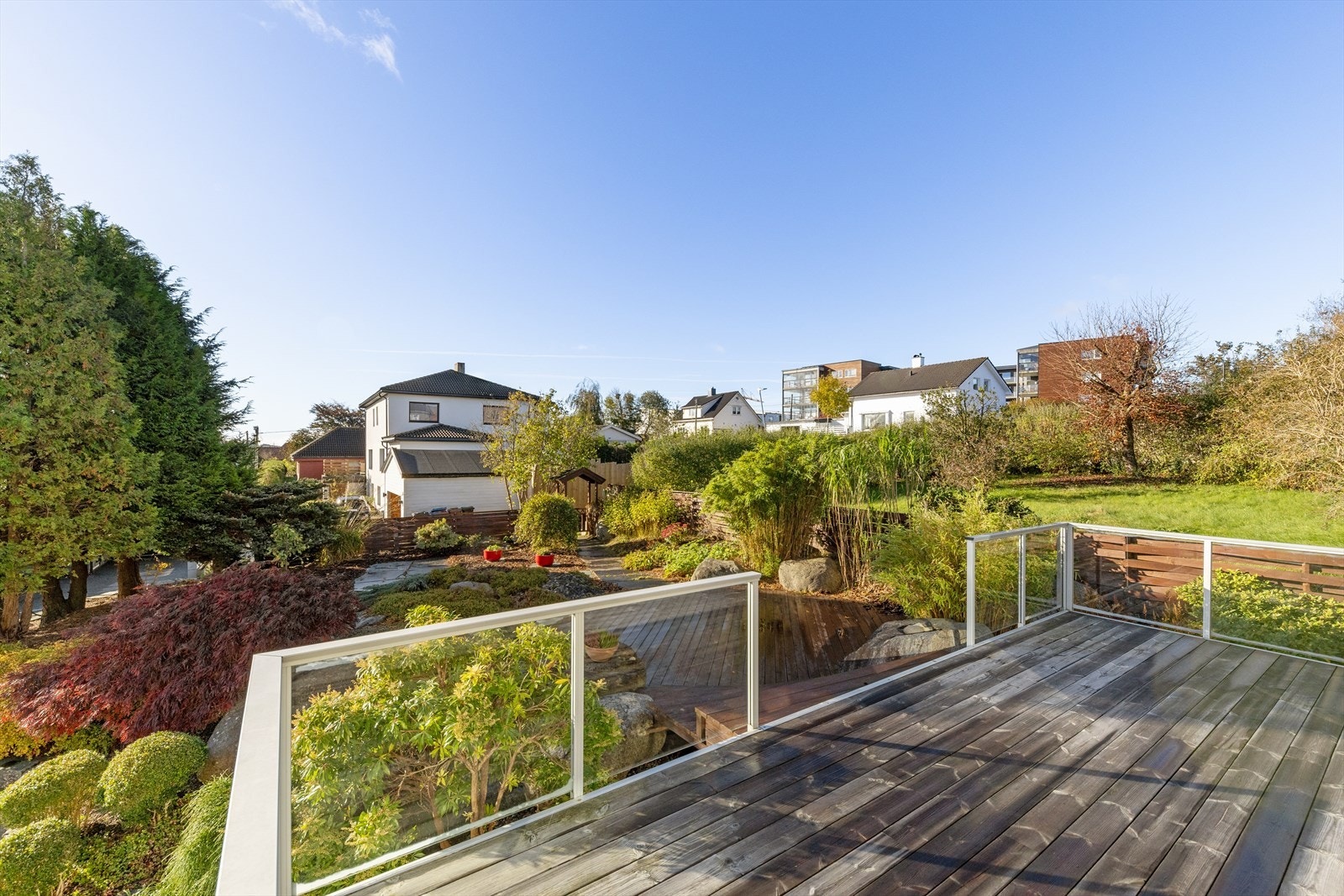 Terrassen med glassrekkverk gir en flott utsikt over den velstelte hagen og nærområdet. Galleribilde