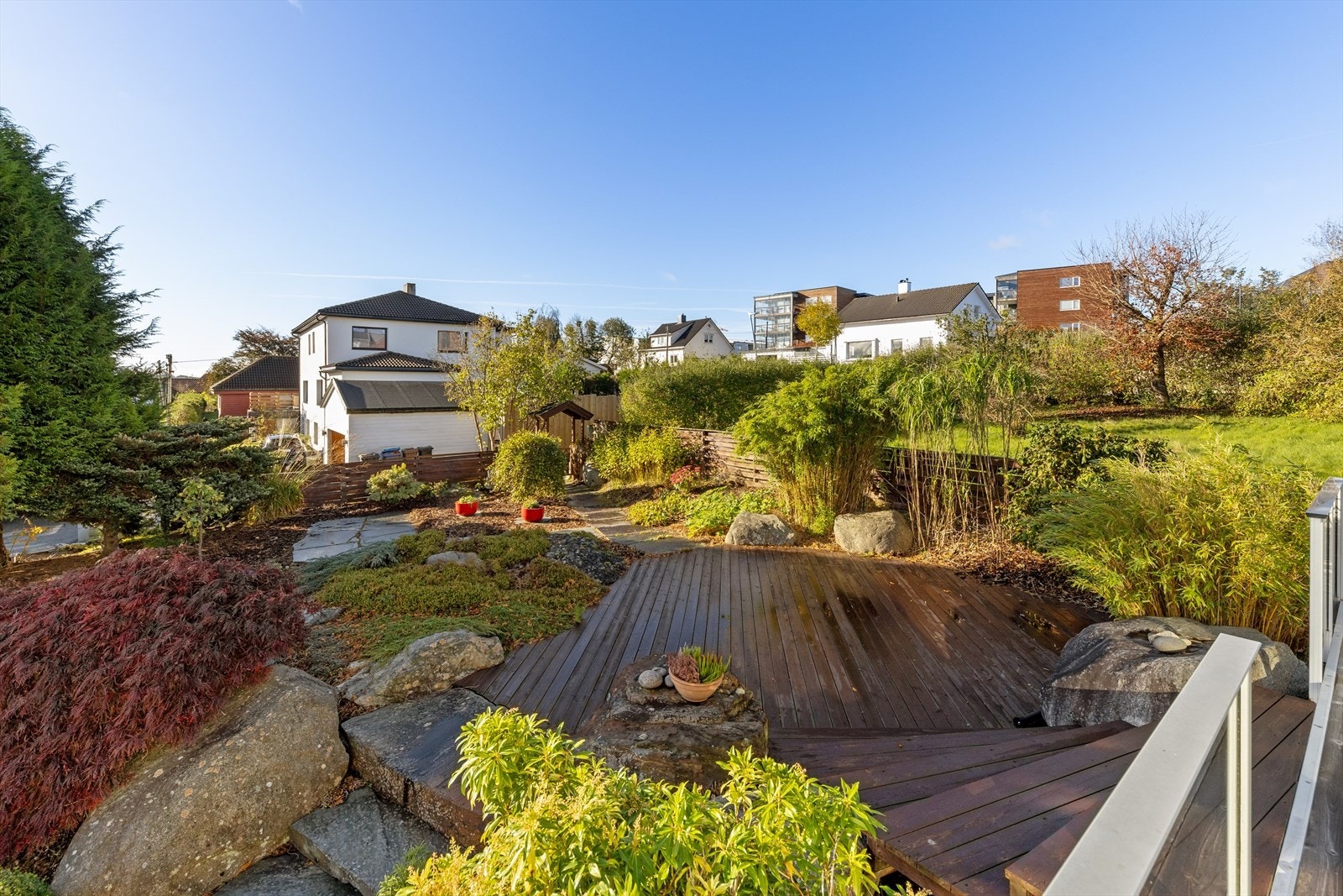 Hagen er pent opparbeidet med steinbelagte stier og frodig beplantning som gir en innbydende atmosfære. Galleribilde