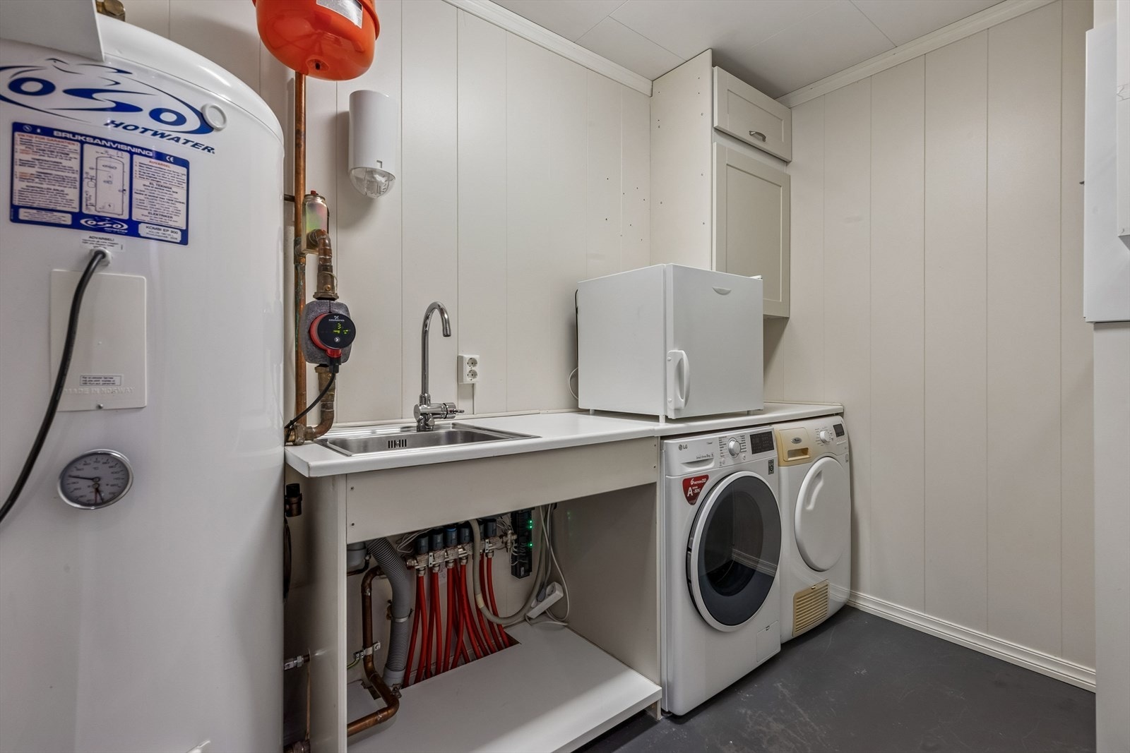 Praktisk teknisk rom med opplegg for vaskemaskin, stoppekran og en varmtvannstank på 200 liter. Galleribilde