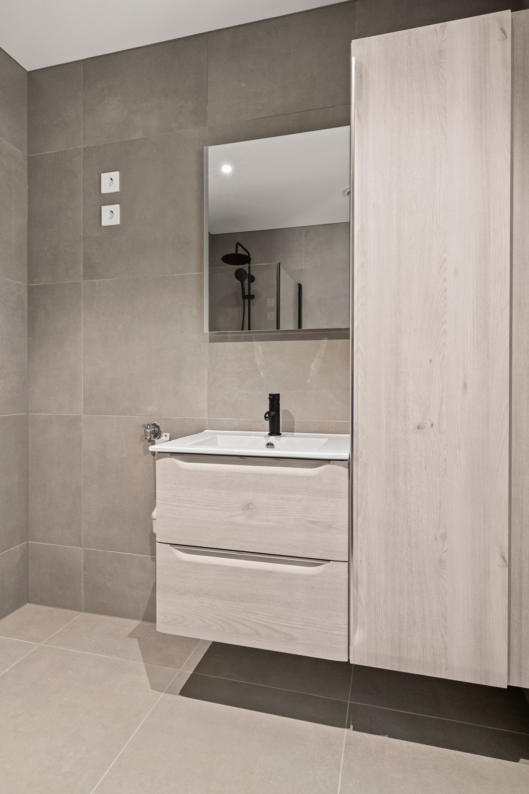 Baderomsinnredning med heldekkende servant, skuffer og et praktisk høyskap for oppbevaring. Galleribilde