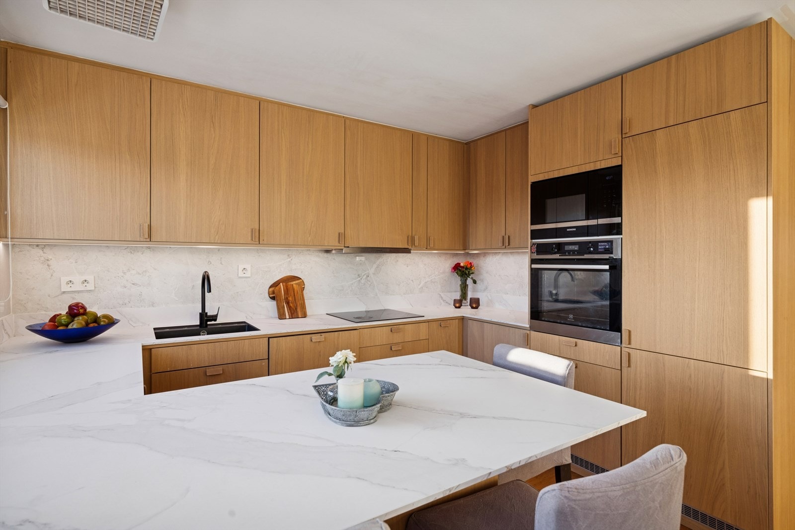 Kjøkkeninnredningen er moderne med lyse, slette fronter og laminert benkeplate. Galleribilde