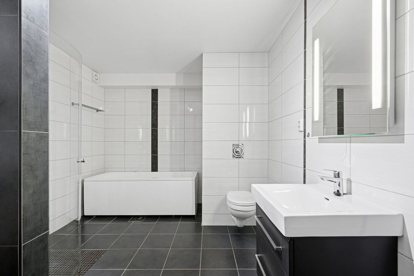 Romslig bad med badekar, dusjhjørne og opplegg til vaskemaskin Galleribilde