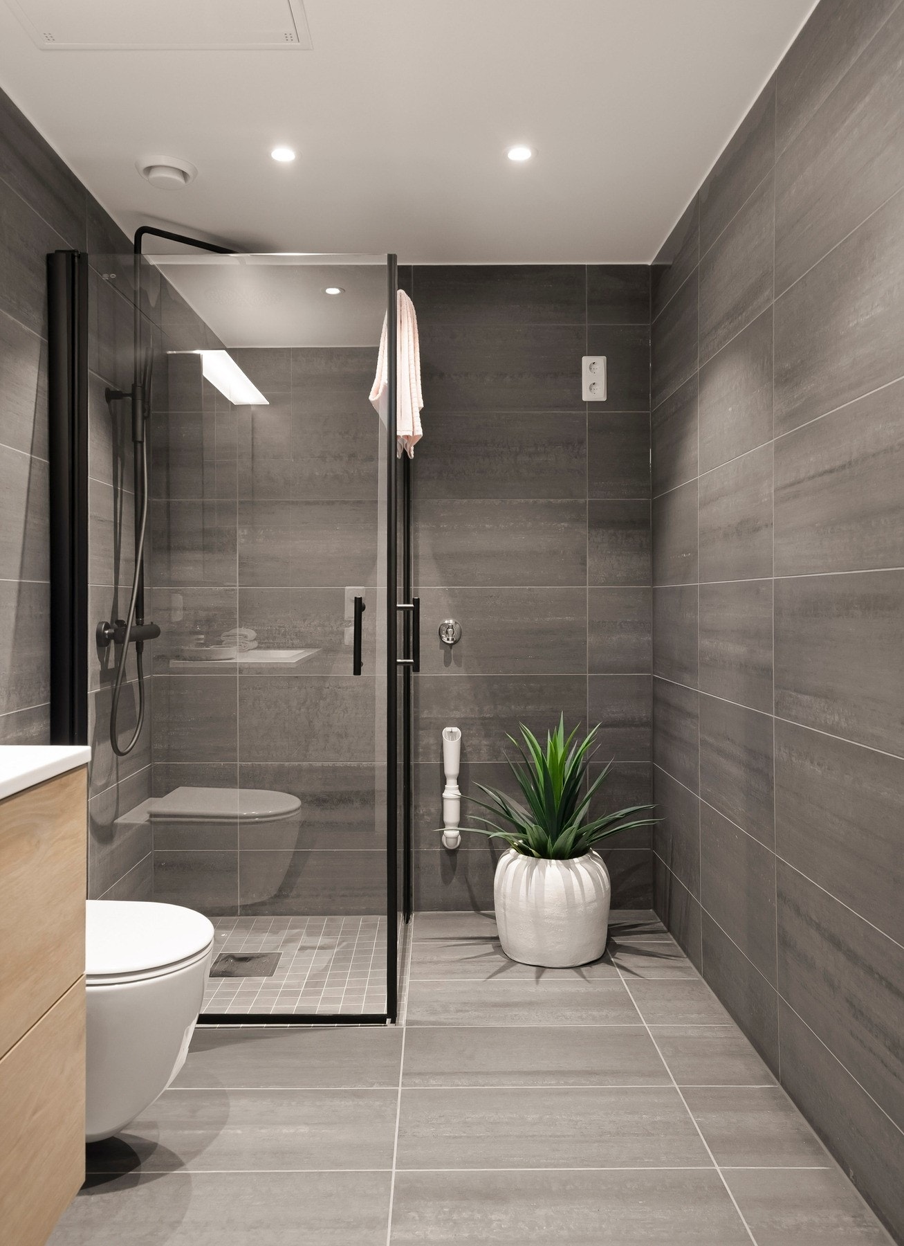 Badet er innredet med vegghengt toalett, servant med skuffer under og dusjhjørne med innfellbare glassdører og regnfallsdusj. Det er opplegg for vaskemaskin/tørketrommel Galleribilde