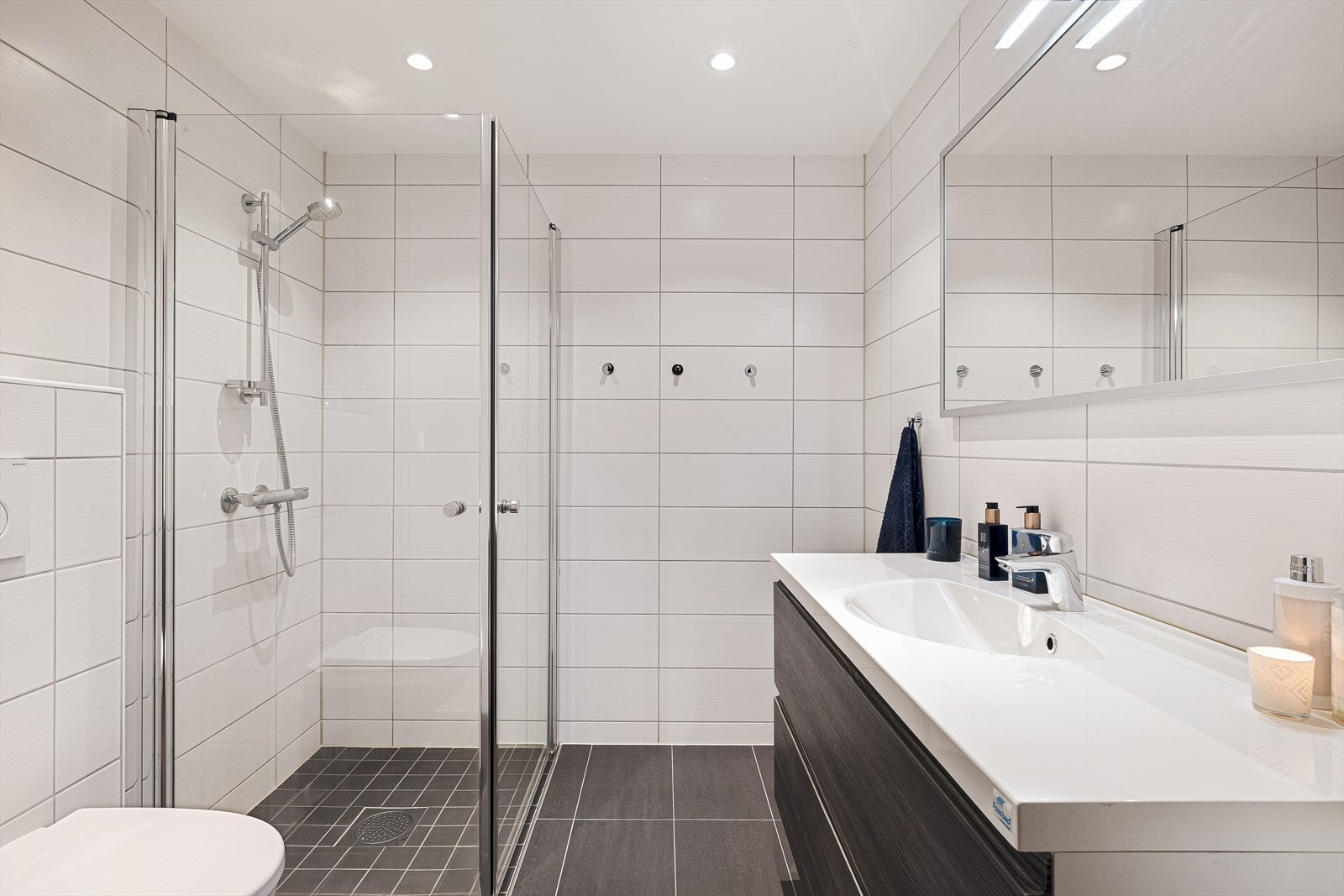 Pent, helfliset bad med vegghengt toalett, dusjhjørne og baderomsinnredning Galleribilde