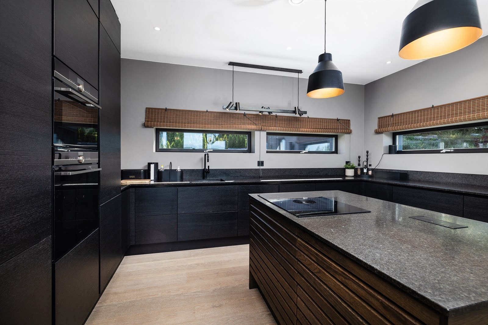 Kjøkkenet har et moderne preg og har slett vegg med backsplash av stein over kjøkkenbenken og gjennomtenkte sorte detaljer. Galleribilde