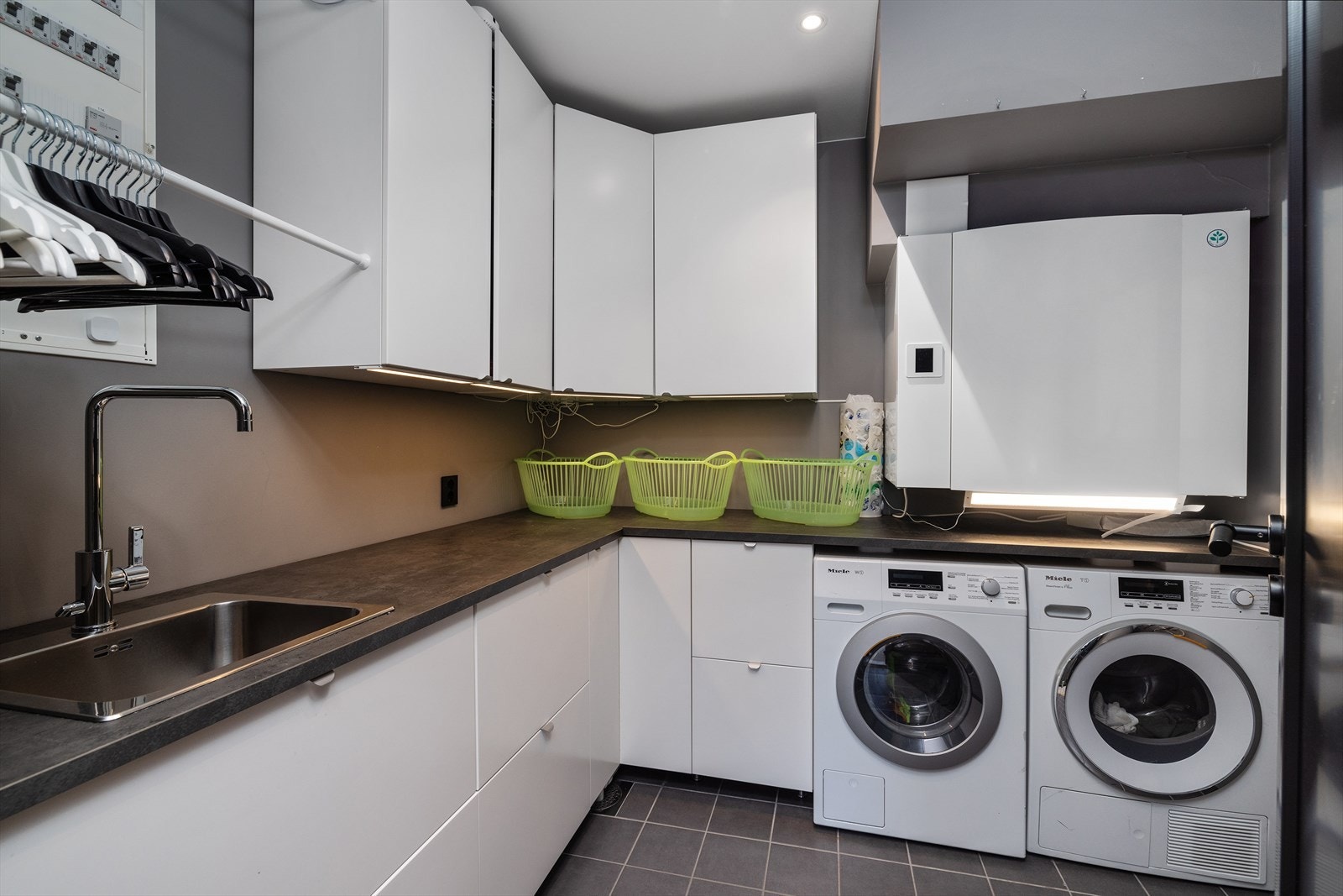 Praktisk innredet vaskerom i underetasjen med en romslig innredning med over og underskap. Rommet har opplegg for vaskemaskin og tørketrommel. Galleribilde
