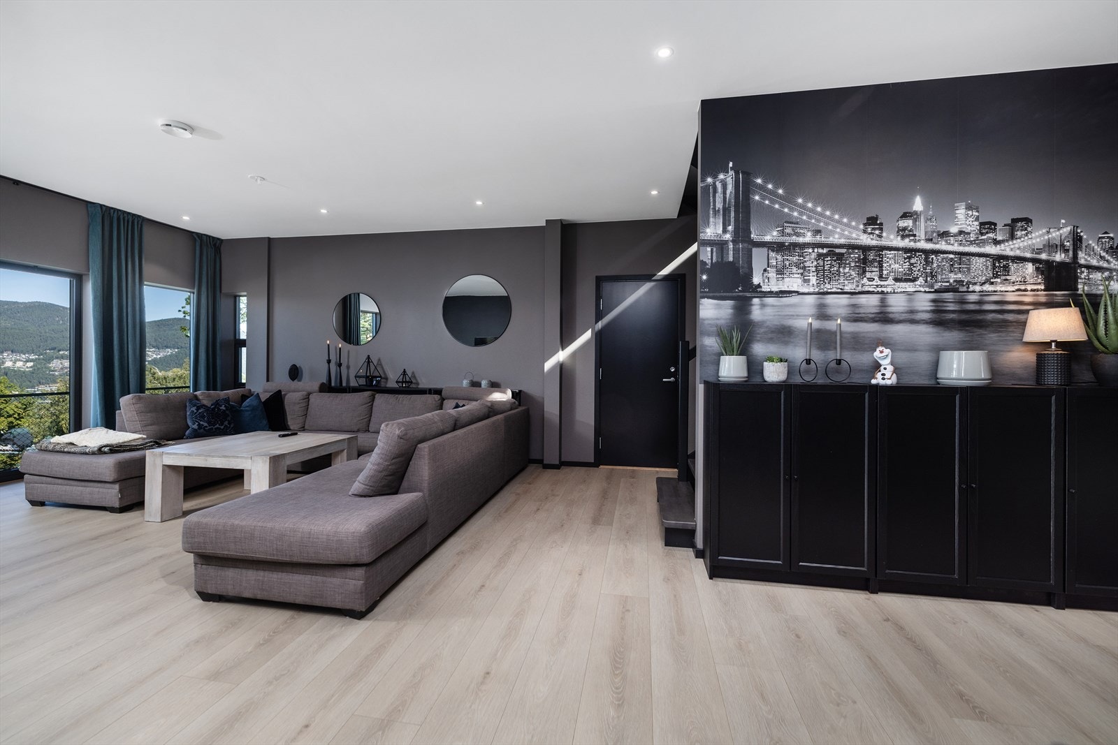 Stuen i underetasjen har 1-stavs laminat på gulv, slette vegger malt i grå fargetoner og en elegant New York tapet på kortveggen, samt dimbare downlights i tak. Galleribilde