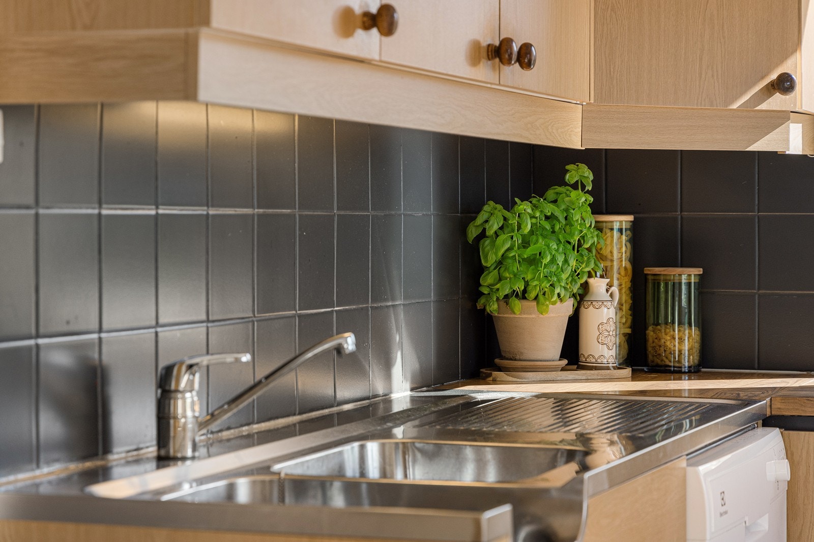 Veggene over benken er kledd med sortmalte fliser, og under overskapene er det montert god arbeidsbelysning. Galleribilde