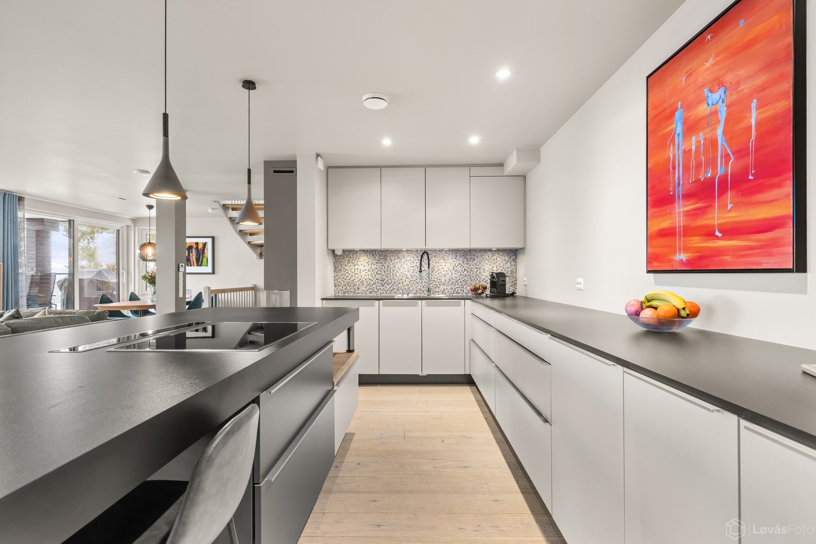 Innredningen har grå, glatte fronter, mørkere høyskap, høytrykkslaminert benkeplate og nedfelt oppvaskkum i rustfritt stål. Galleribilde