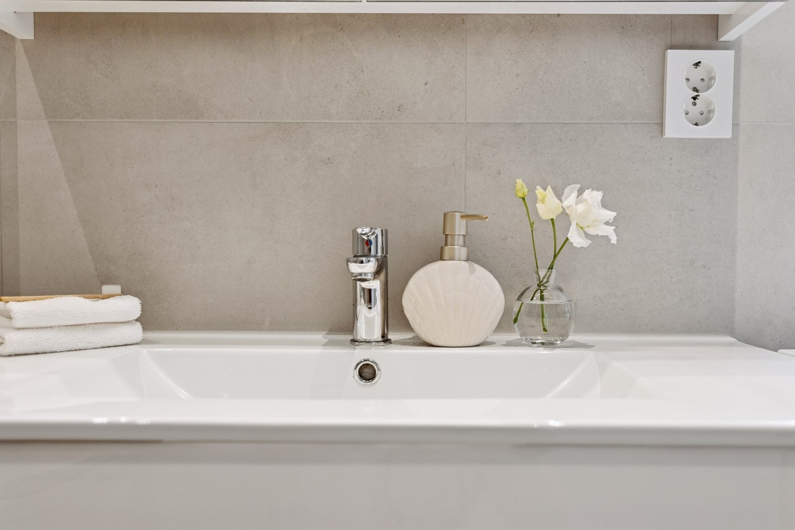 Badets fargevalg gir assosiasjoner til "spa tema". De lune, matte og delikate gulvflisene med varmekabler skaper en match til de ellers like veggflisene i moderne storformatdesign. Galleribilde