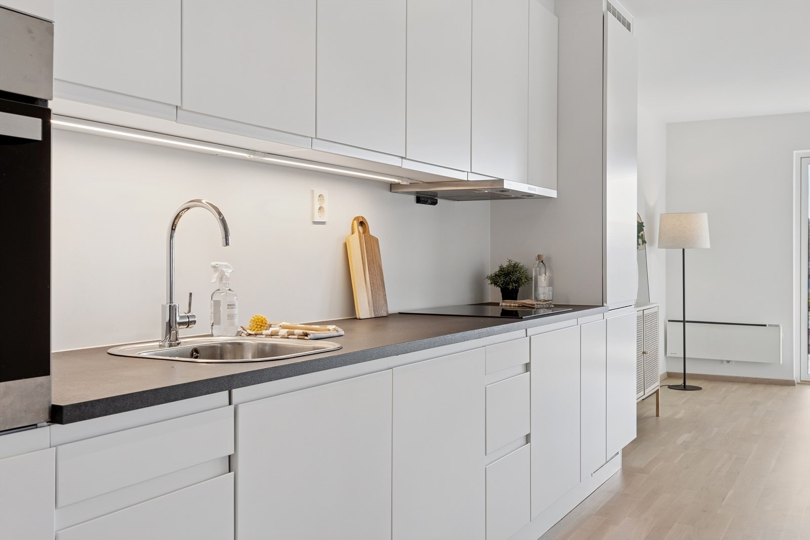 Med sosial og åpen løsning kan man kokkelere mens samtalen holdes i gang med leilighetens gjester enten de sitter i sofa-/loungegruppen eller rundt spisestuedelens bord. Galleribilde