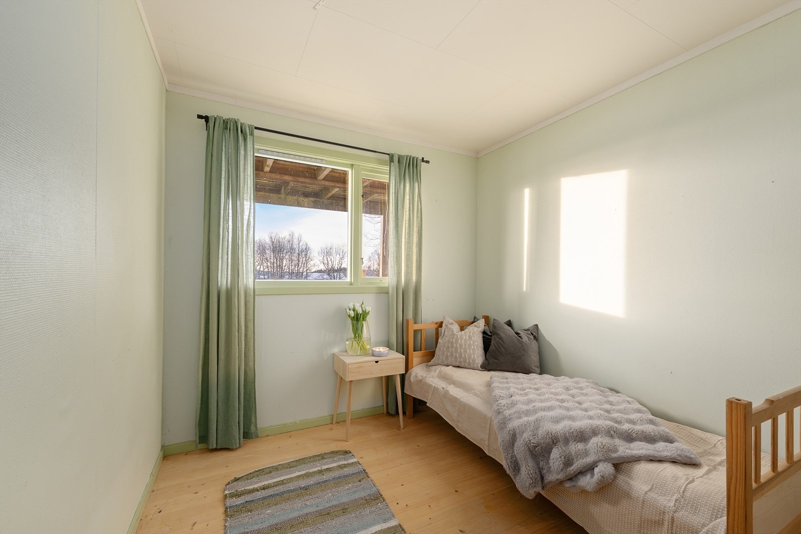 Det andre soverommet i underetasjen har tregulv og vindu mot hagen. Galleribilde