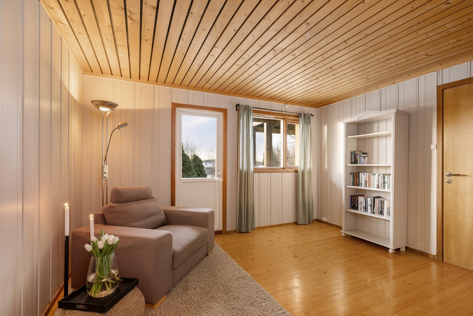 Gangen i kjeller er innredet som en liten ekstra stue. Herfra er det utgang til hagen. Galleribilde