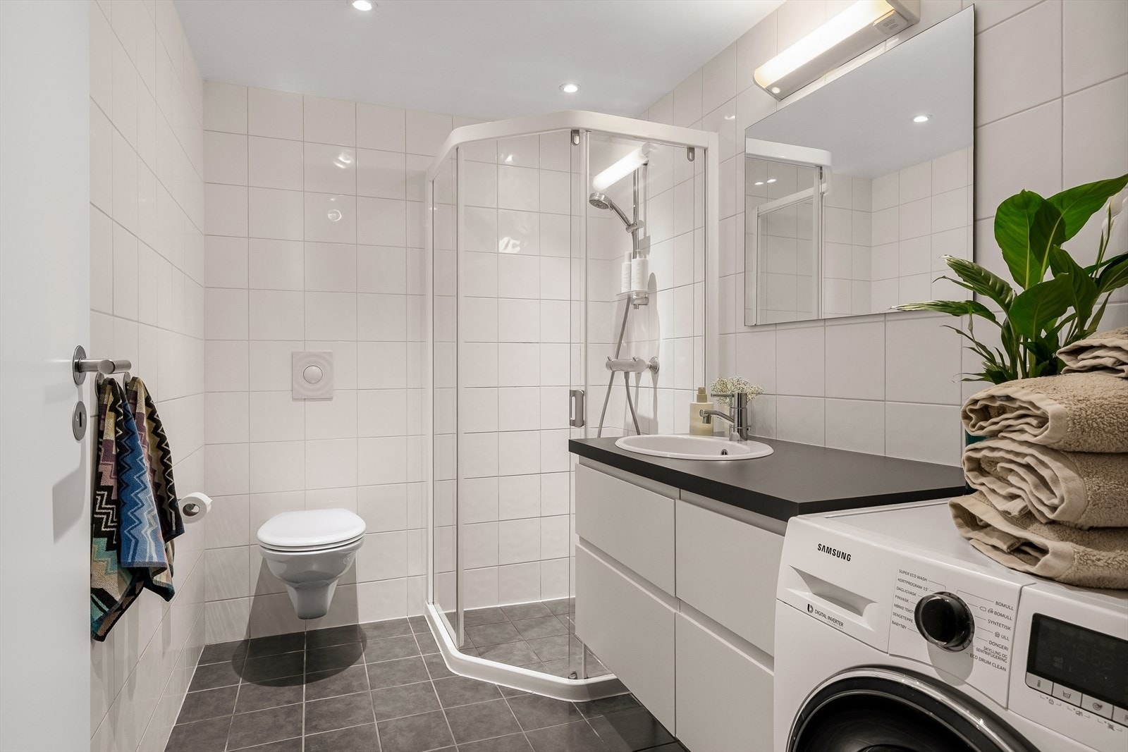 Badet er utstyrt med baderomsinnredning med nedfelt servant, vegghengt toalett samt dusjløsning med dusjvegger/hjørne. Galleribilde