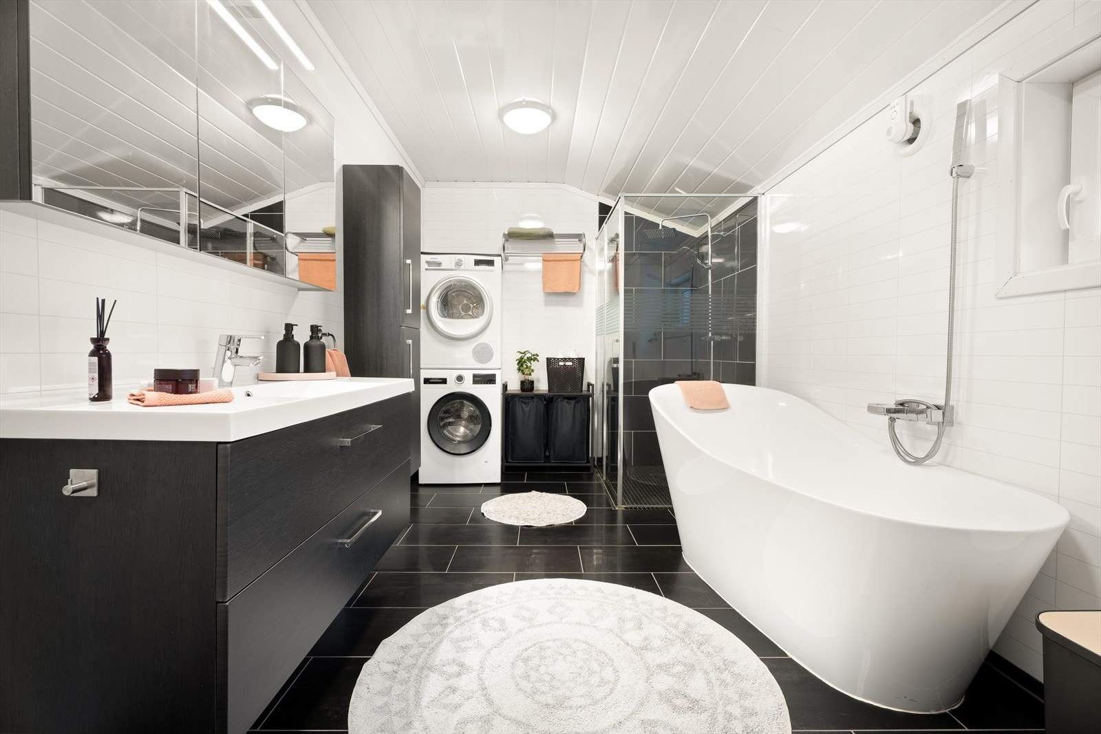 Badet er utstyrt med servantinnredning, dusjhjørne med glassvegger, opplegg for vaskemaskin, badekar og vegghengt toalett. Galleribilde