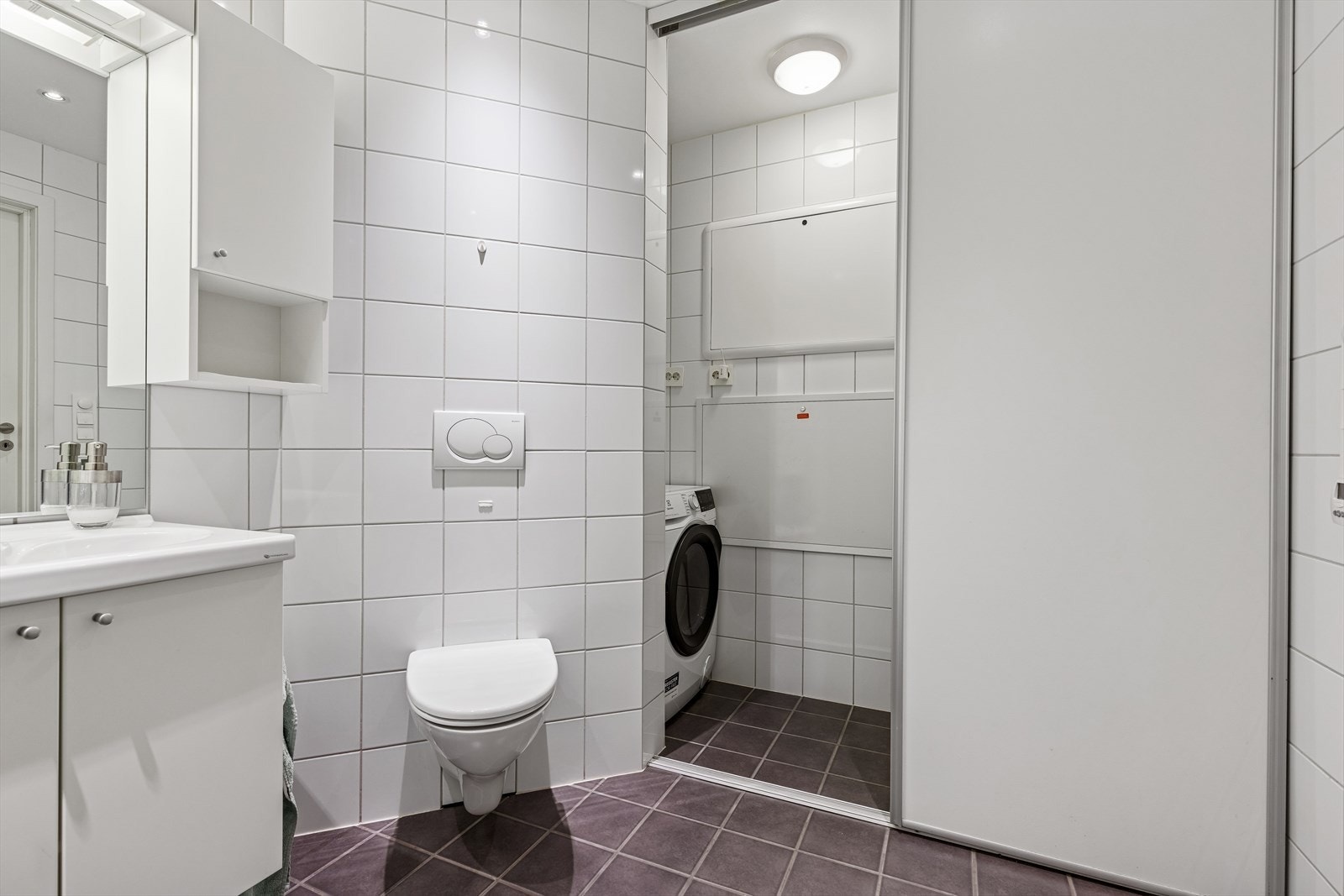 Meget praktisk løsning med skyvedør inn til avgrense del som naturlig brukes til oppbevaring og vaskemaskin. Galleribilde