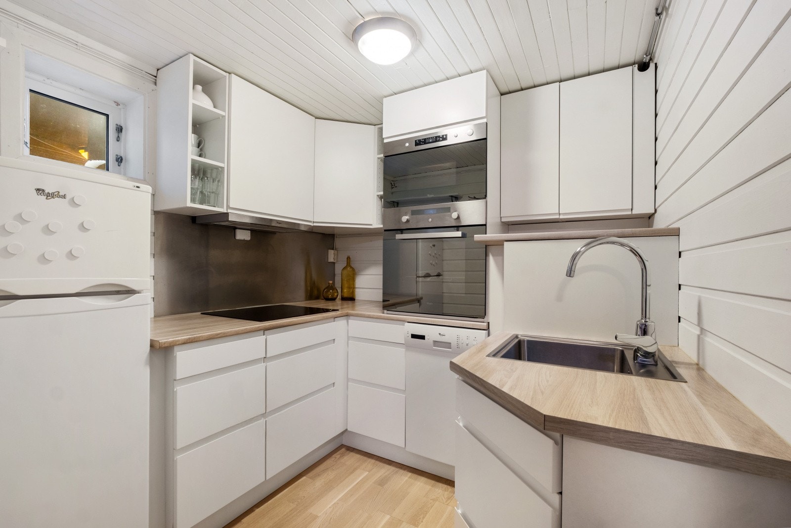 Kjøkkenet har innredning med glatte fronter og benkeplate i laminat - Hvitevarene består av integrert komfyr, integrert mikro, integrert koketopp og frittstående kombiskap Galleribilde