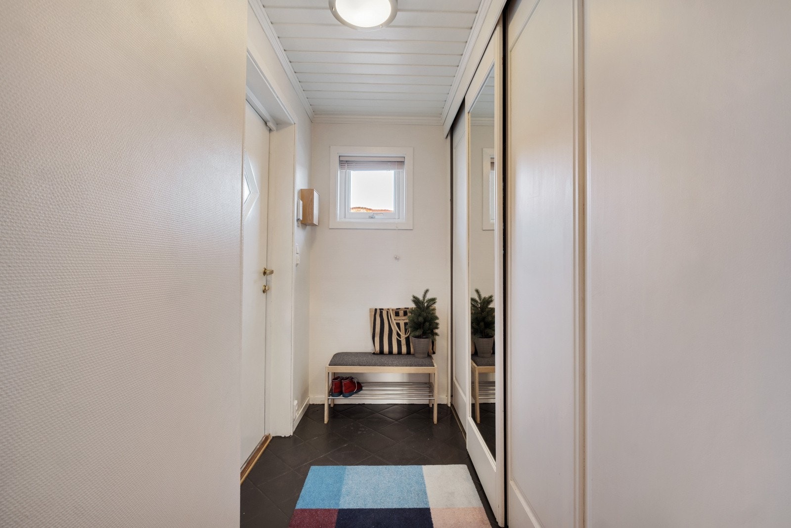 Du ønskes velkommen inn i en hyggelig flislagt entré med gulvvarme og en romslig skyvedørsgarderobe Galleribilde