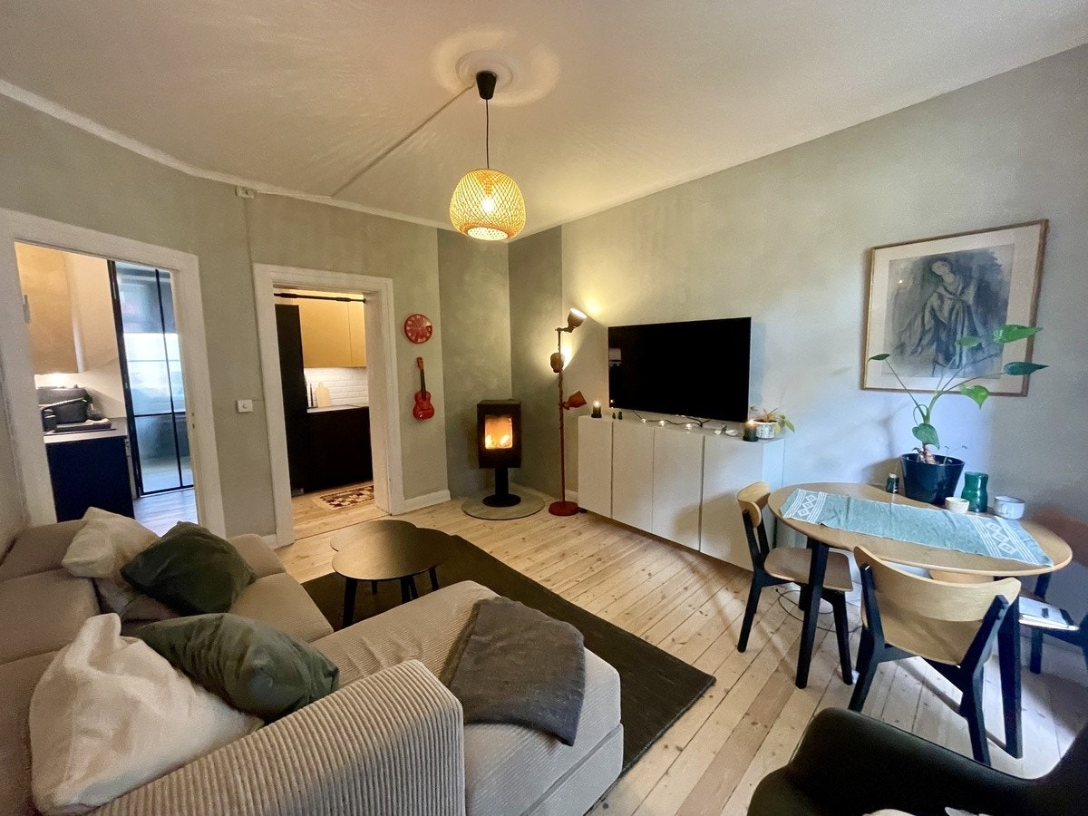 Romslig stue med sofa, TV, spisebord og peisovn. Galleribilde