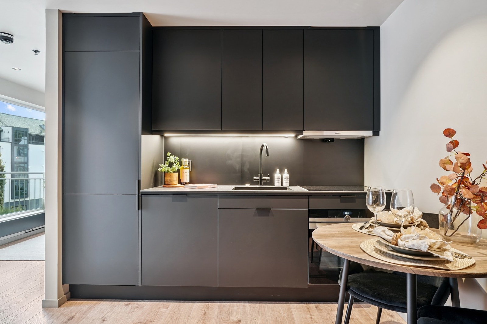 Praktisk kjøkken fra Specup med sorte fronter og en laminat benkeplate med underlimt oppvaskkum av kompositt. Galleribilde