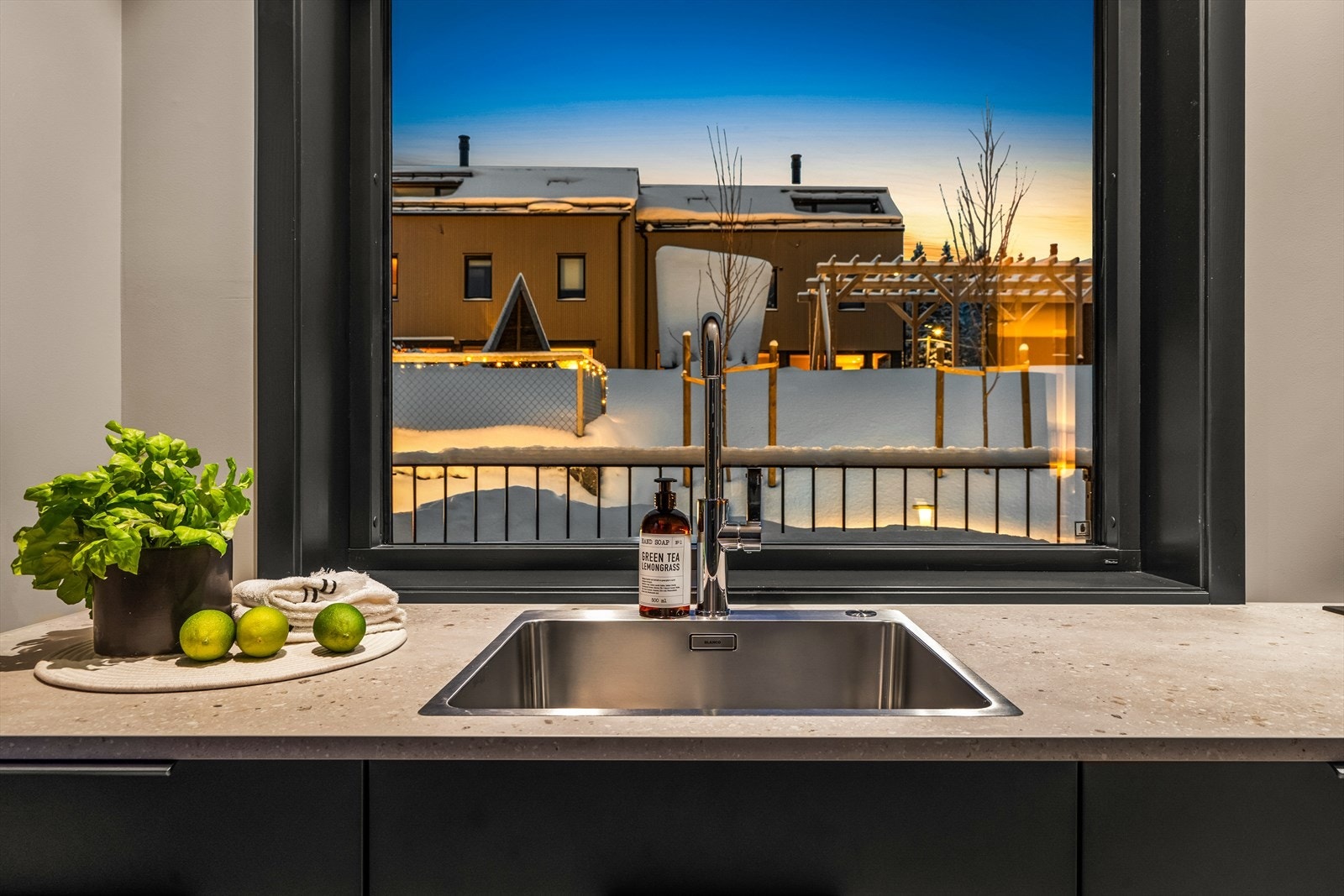 Kjøkkenet har mørke, slette fronter og Terrazzo 20 mm laminat benkeplate med nedfelt oppvaskkum Galleribilde