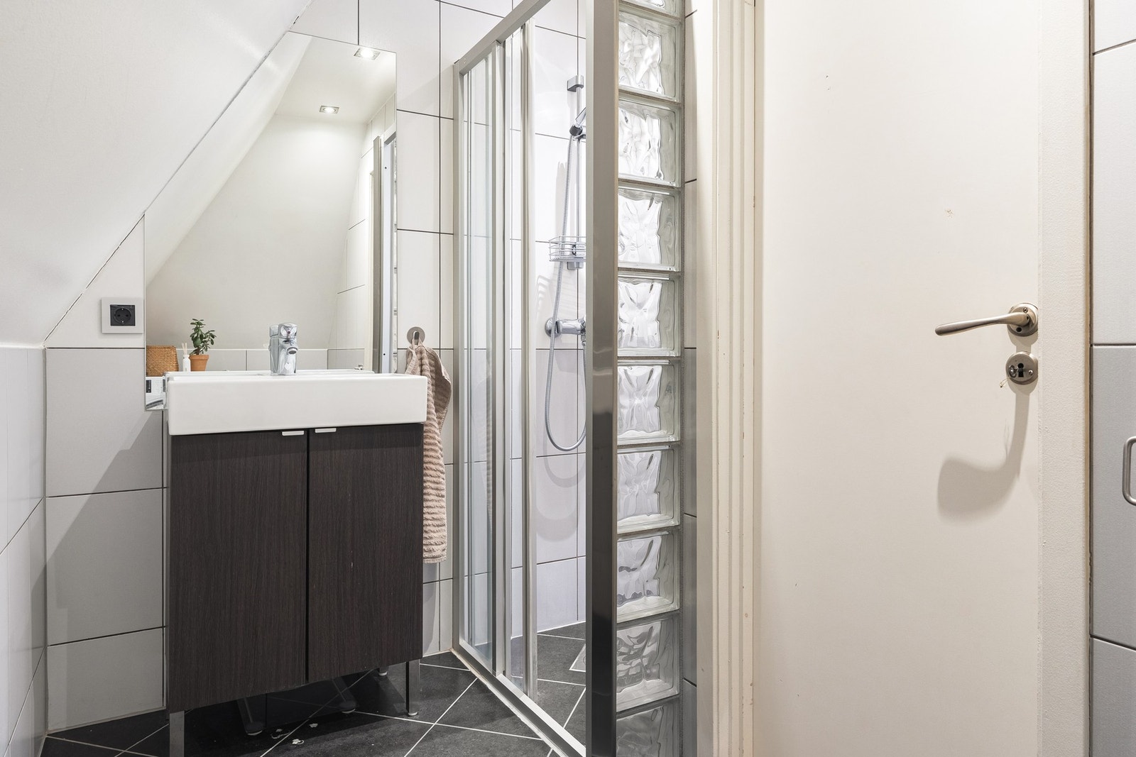 Badet er helfliset og inneholder dusjhjørne, toalett, servant med skap og opplegg for vaskemaskin. Galleribilde