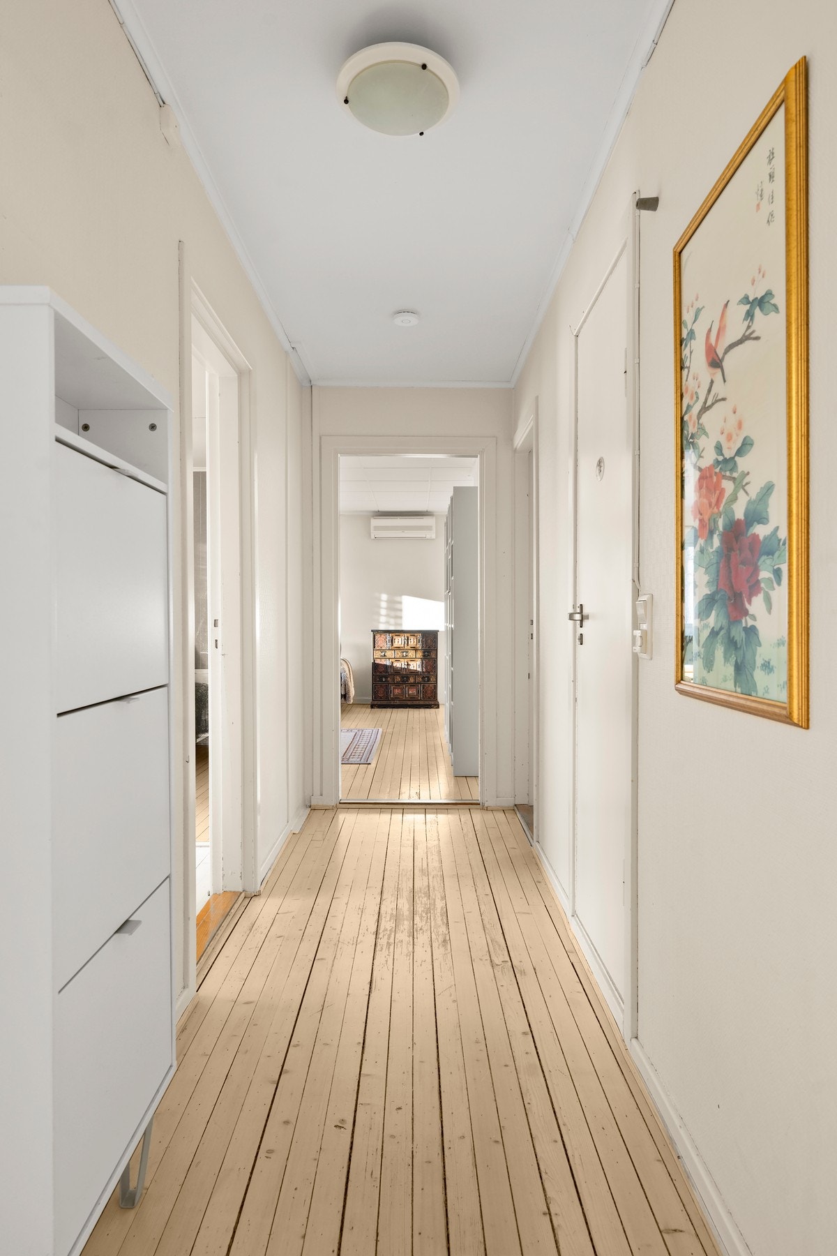 Lang gang med gjennomgående tregulv binder sammen boligens ulike soner på en praktisk måte. Galleribilde