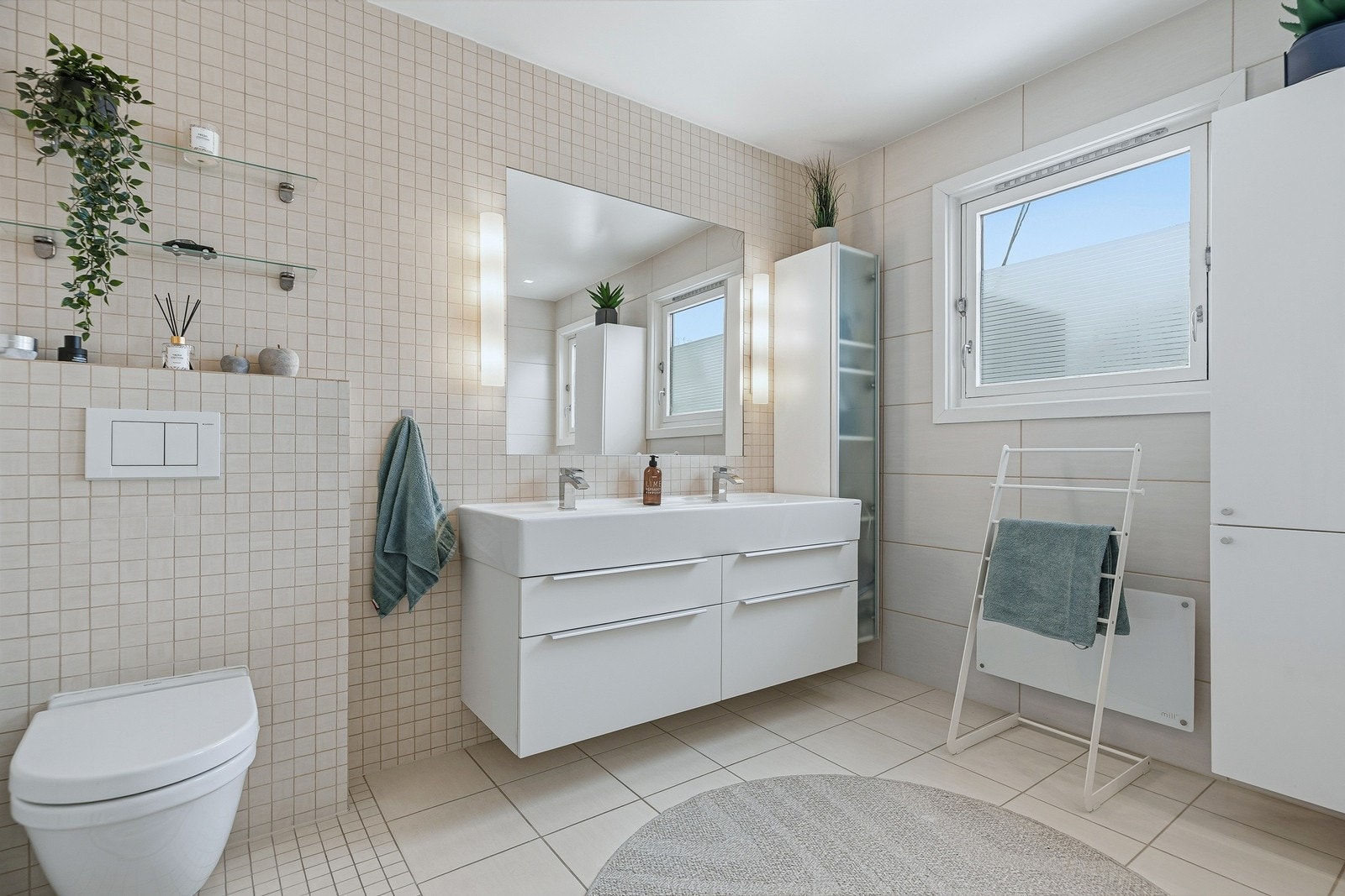 Videre er det vegghengt toalett, dobbel servant samt to høyskap med god oppbevaringsplass. Galleribilde