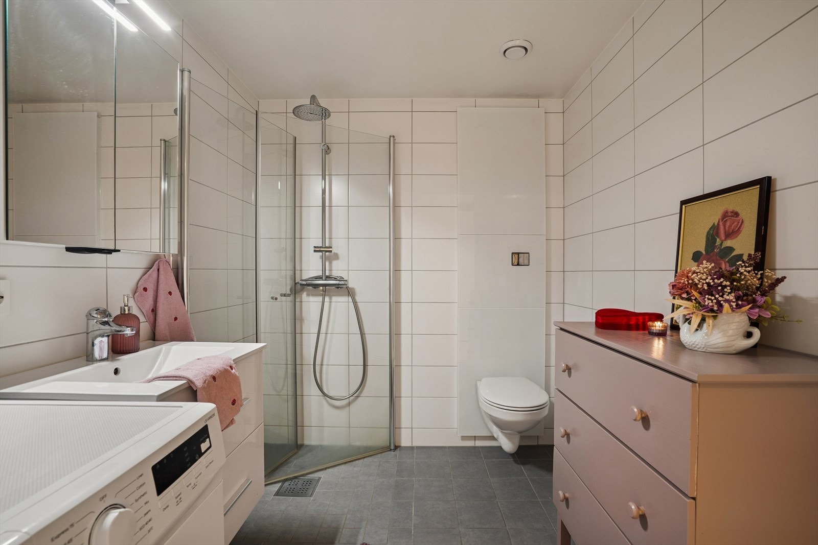 Badet er flislagt med mørke gulvfliser og lyse avlange veggfliser - Her er det oppvarming med elektriske varmekabler Galleribilde