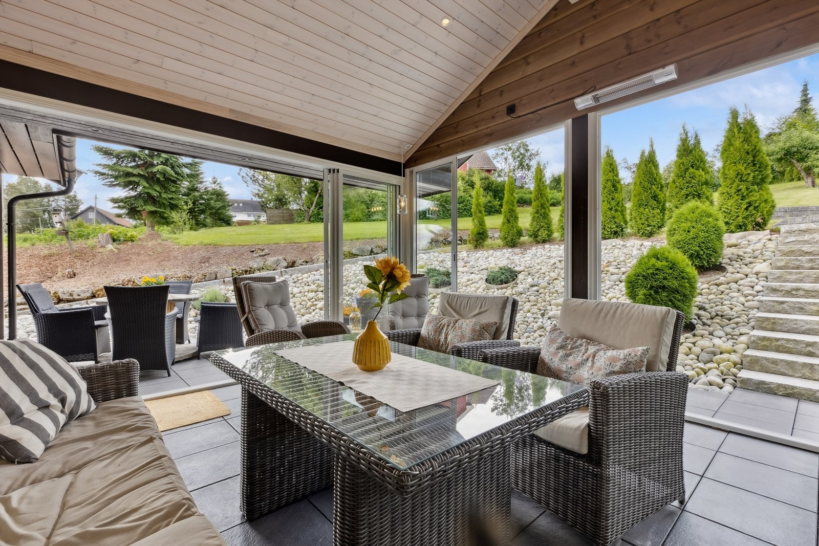 Med skyvedører i glass og stråleovn er dette et komfortabelt rom som kobler inne- og uteområdene sammen. Galleribilde