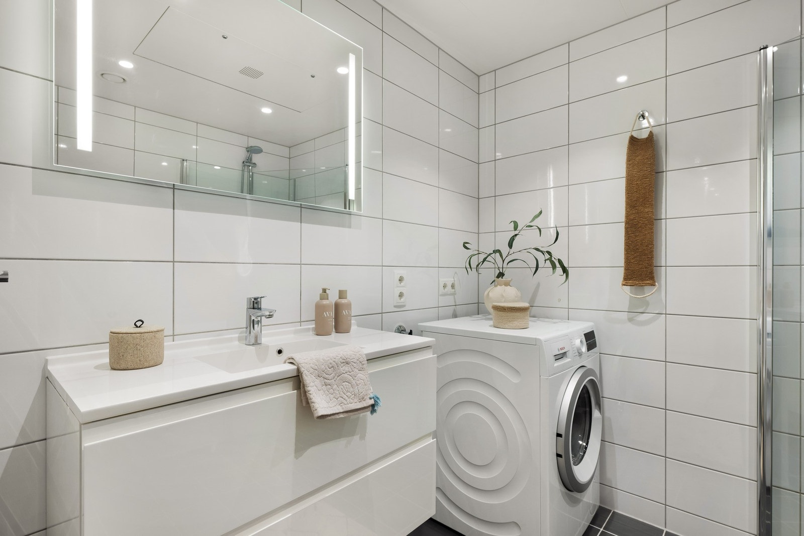 Baderomsinnredningen består av vegghengt toalett, helstøpt servant, skuffer under servant med slette fronter og dusjdører i klart glass. Galleribilde