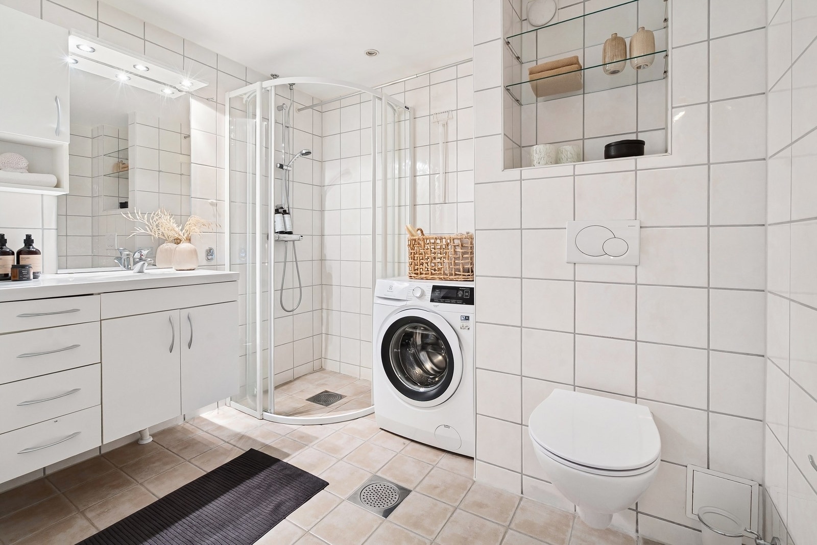 Baderommet har dusjhjørne med skyvedører av glass med dusjarmatur tilkoblet hånddusj. Her er det også god plass til vaskemaskin. Galleribilde