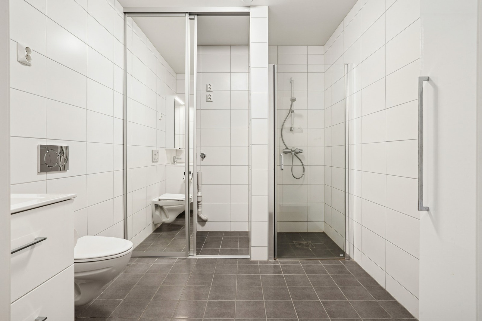 Her har du praktisk plass til vaskemaskin og tørketrommel bak skyvedører og dusjhjørne med innfellbare glassdører. Galleribilde