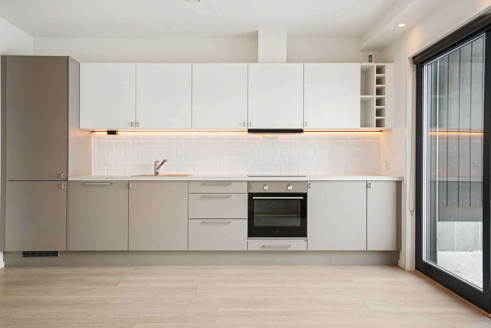 Kjøkken med åpen løsning mot stue fra byggeår. Her får du kjøkkeninnredning med glatte fronter og laminert benkeplate. Galleribilde