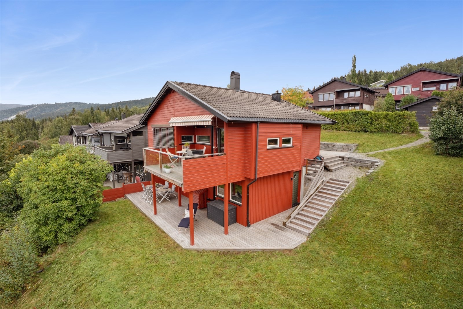 Tomten er pent opparbeidet med plen, hekk for skjerming, støttemurer og terrasseplattinger på hver side av boligen. Galleribilde