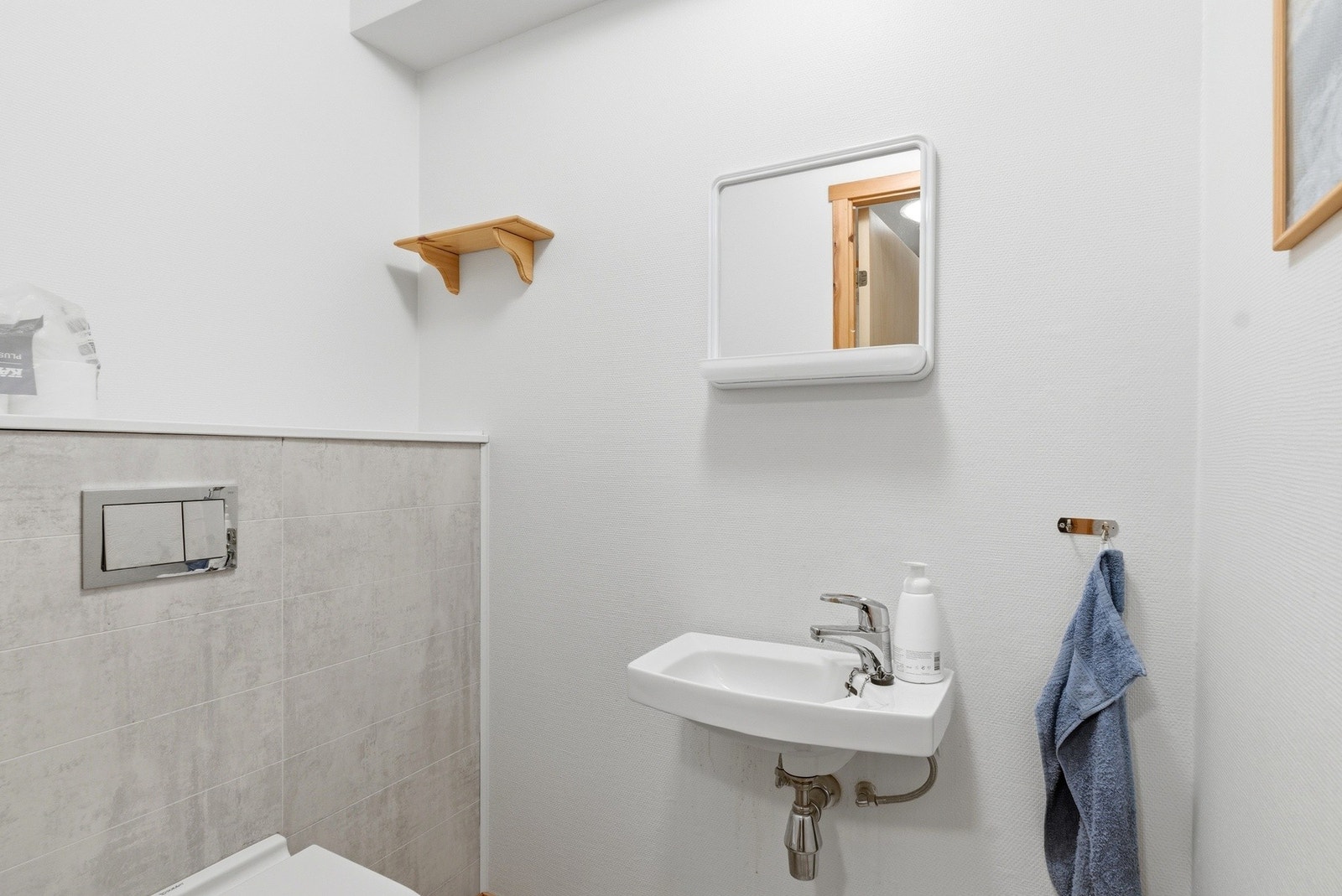 Wc-rom med innebygd toalett og servant på vegg. Galleribilde