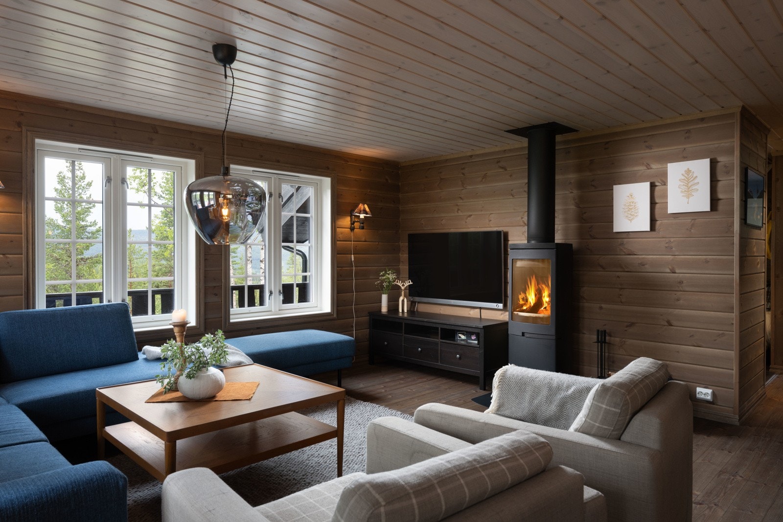 En moderne peisovn fra Nordpeis med isolert stålpipe sørger for varme på kjølige høst og vinterkvelder. Den er både praktisk i forbindelse med oppvarming av hytten, men utgjør også et pent møbel i stuen. Galleribilde