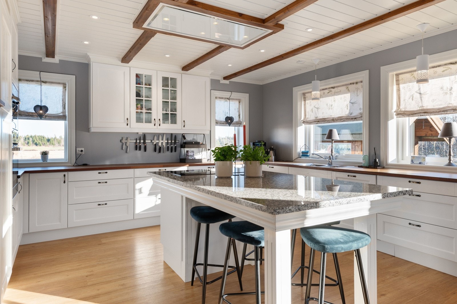 Stort kjøkken med hvite profilerte fronter og heltre benkeplate, det er nedfelt stålvask med ettgreps blandebatteri. Galleribilde