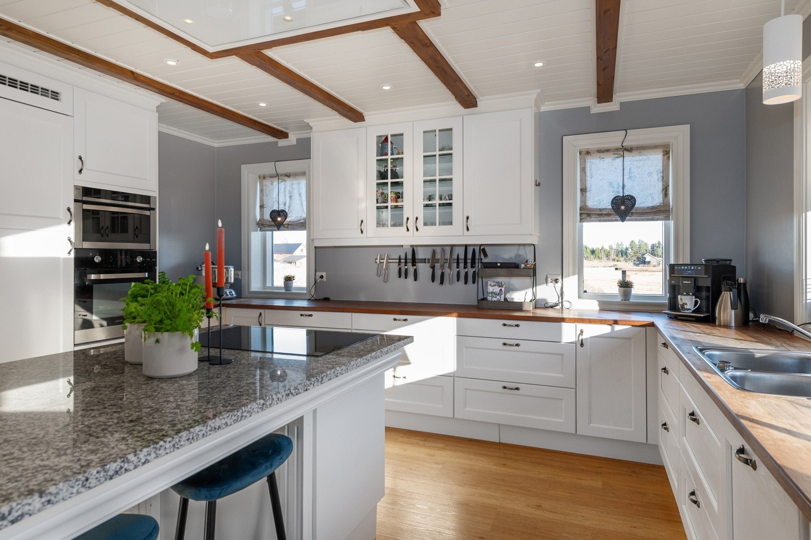 Kjøkkenøy med benkeplate av stein. Det er integrerte hvitevarer som kjøl/ fryseskap, oppvaskmaskin, komfyr og stor koketopp. Galleribilde