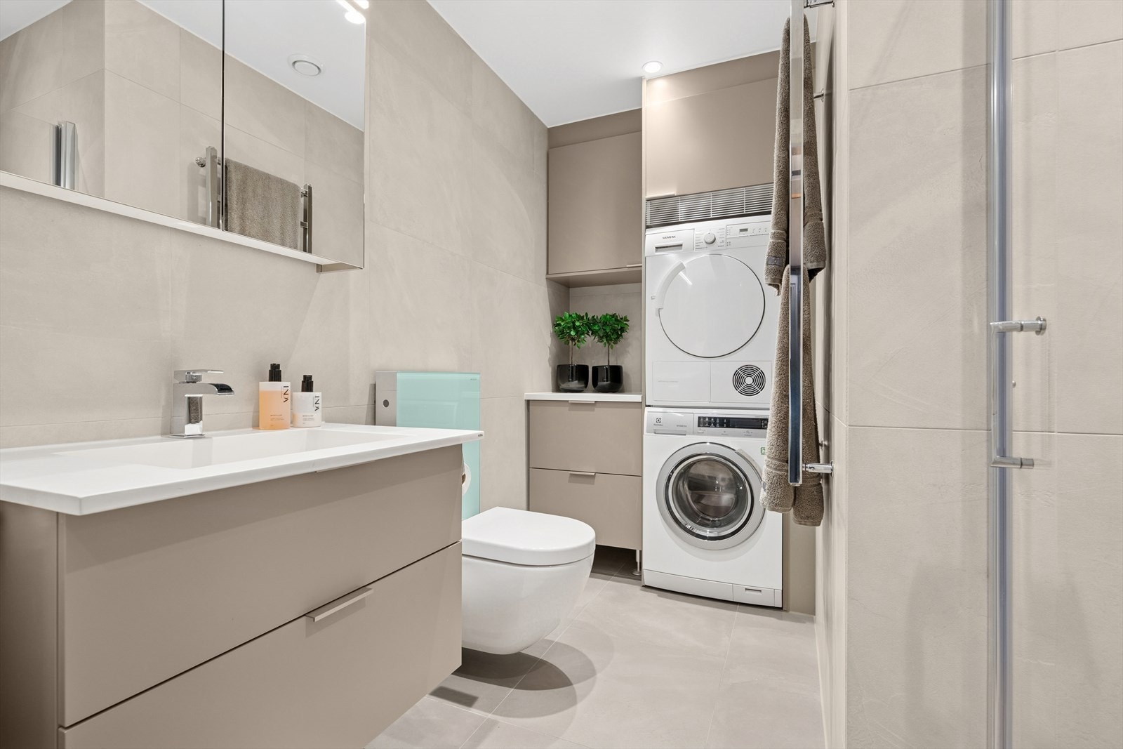 Bad nr. 2 består av speilskap med belysning, servant med skuffeseksjon, veggmontert toalett, dusjnisje, vegghengt håndkletørker og opplegg for vaskemaskin/ tørketrommel. Galleribilde