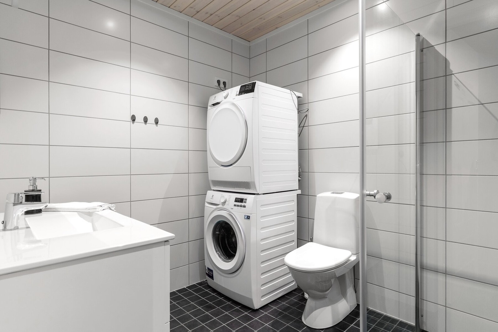 Romslig flislagt bad innredet med behandlet innredning med servanttopp, dusjhjørne og toalett. Badet har opplegg for vaskemaskin. Galleribilde