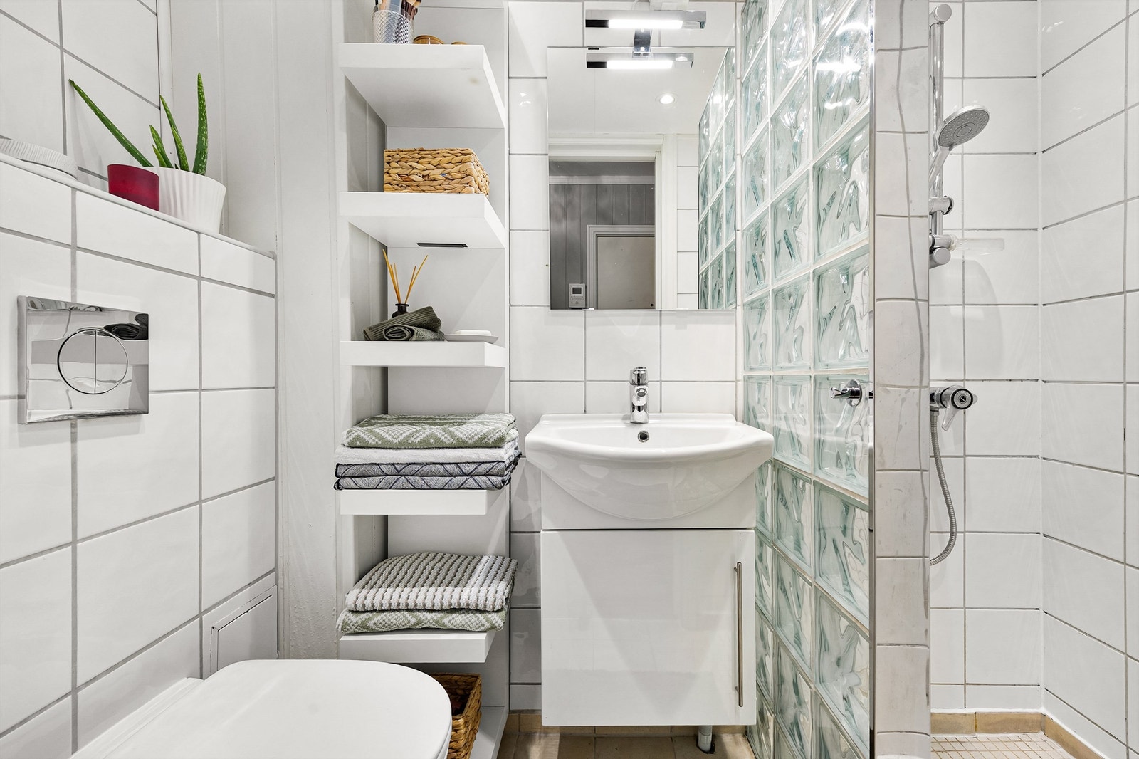 Baderomsinnredning av servant med underskap samt speil med belysning. Ekstra oppbevaring i praktisk hylle Galleribilde