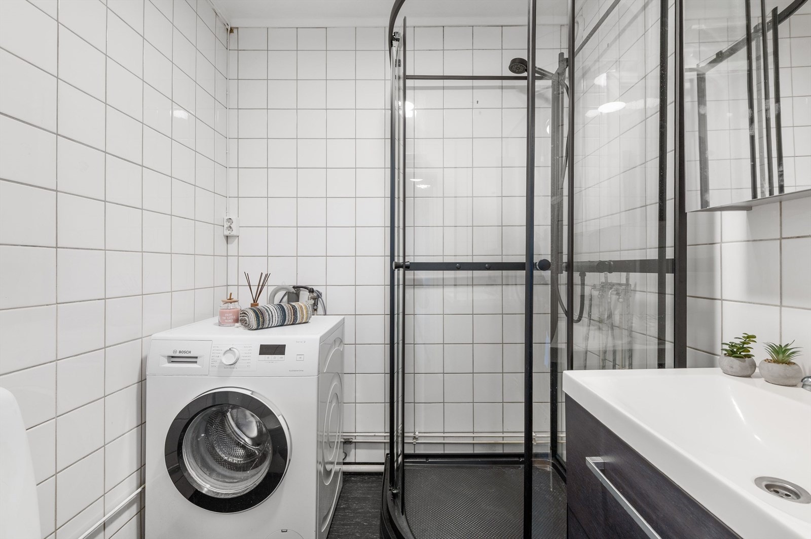 Dusjkabinett og vaskemaskin gir praktisk funksjonalitet på badet. Galleribilde