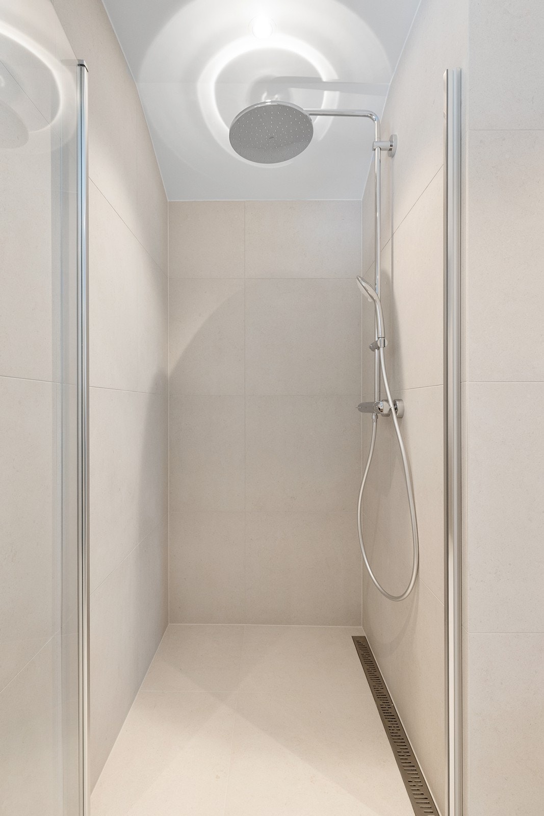 Romslig dusjhjørne med regnfalldusj med glassdør. Galleribilde