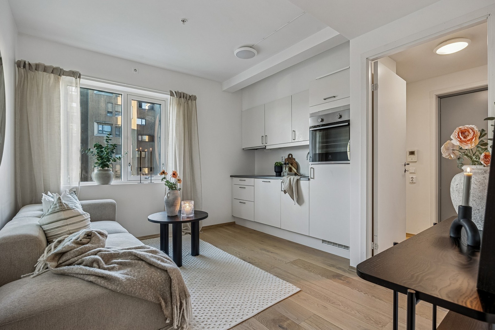 Stue og kjøkken er samlet i en åpen og sosial løsning med gulvvarme, store vindusflater og moderne kjøkkeninnredning med mekanisk avtrekk. Galleribilde