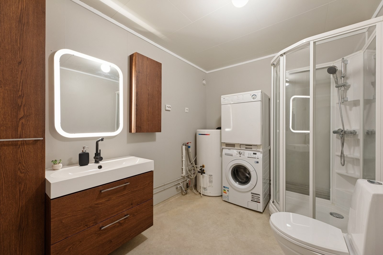 Badet er kombinert vaskerom med praktisk opplegg for både vaskemaskin og tørketrommel. Galleribilde