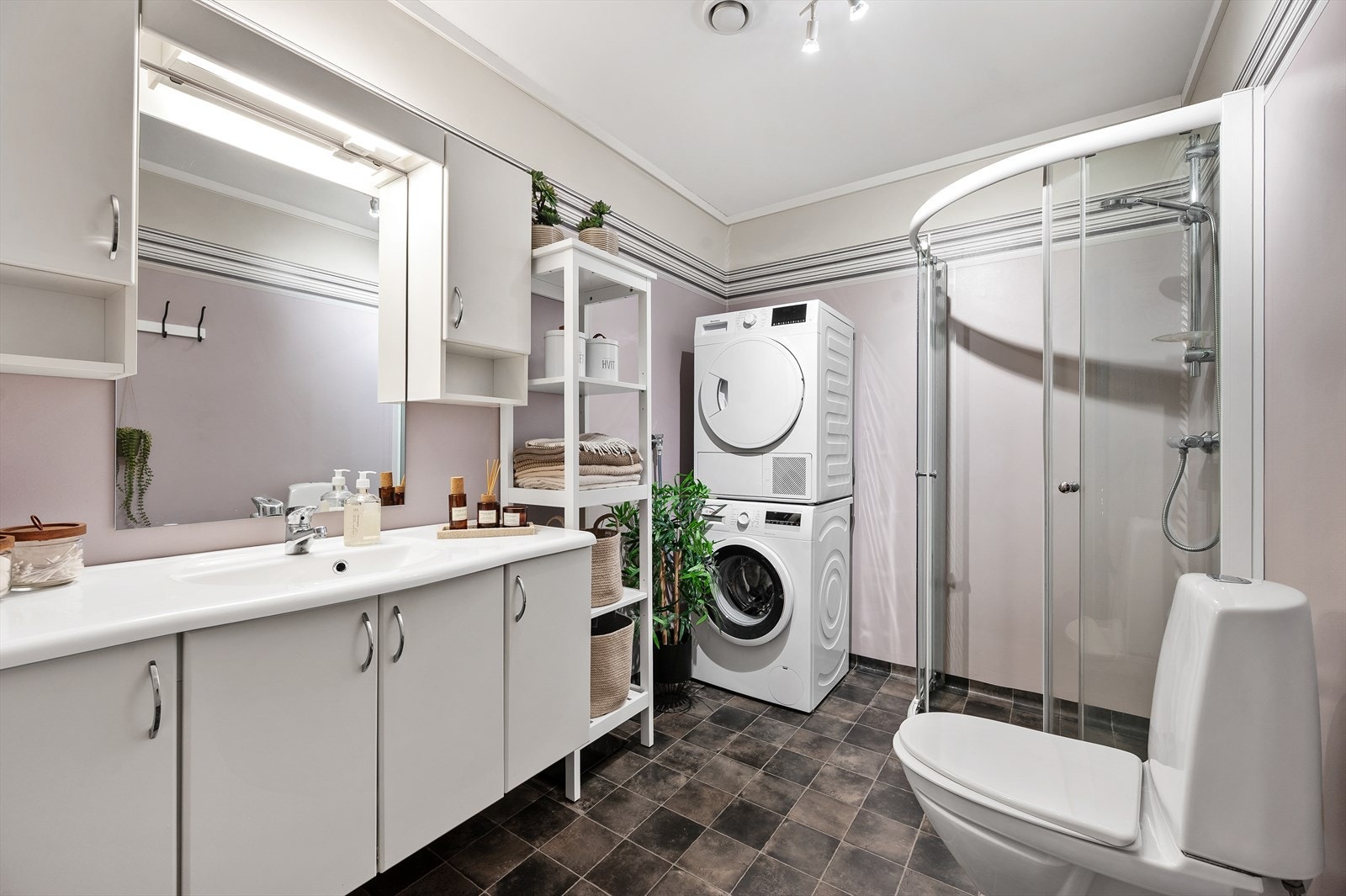 Bad innredet med dusjhjørne, servant i møblement og opplegg for vaskemaskin. Galleribilde